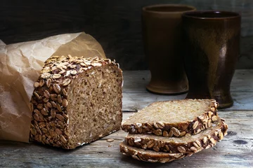 Selbstklebende Fototapeten wholegrain bread with seeds on weathered wood, dark background © Maren Winter
