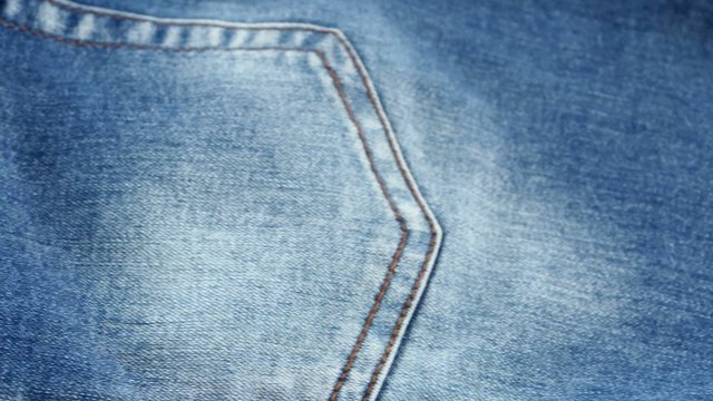 Blue jeans pocket on brown cloth, cam moves to the left, close
