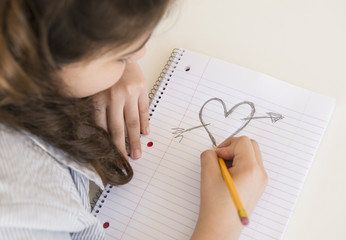 Hispanic girl doodling heart and arrow
