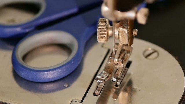Old working silver sewing machine with blue scissors, close up