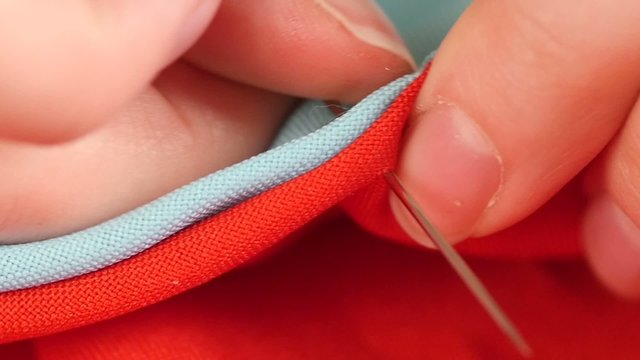Woman`s hands sewing with needle, white thread and thimble on