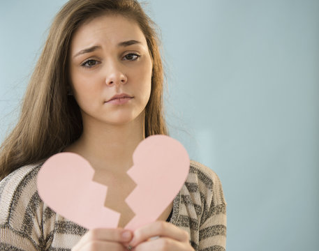 Hispanic girl holding broken heart shape