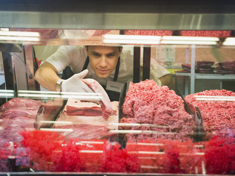 Hispanic butcher at meat counter of grocery store