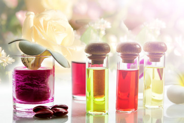 Bottles of natural aroma oil on flowers background