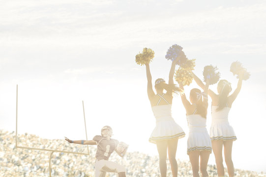 Caucasian cheerleaders on sidelines at football game