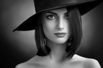 beautiful girl with makeup in hat and earrings, black and white