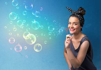 Pretty lady blowing colorful bubbles on blue background