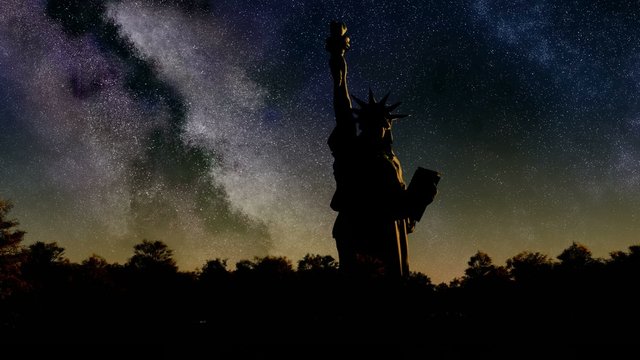 Liberty statue at sunrise from night sky