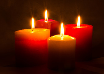 Obraz na płótnie Canvas Four colored candles burning in the dark