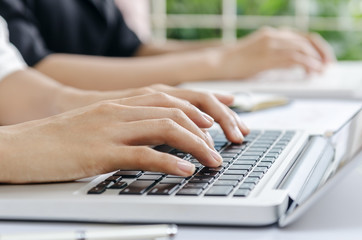 closeup of woman’s hands typing data in laptop