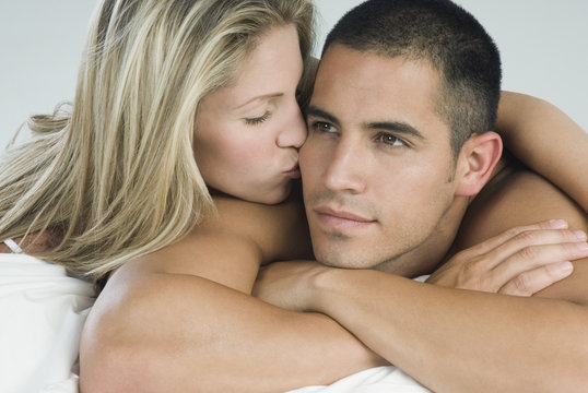 Hispanic woman kissing boyfriend in bed