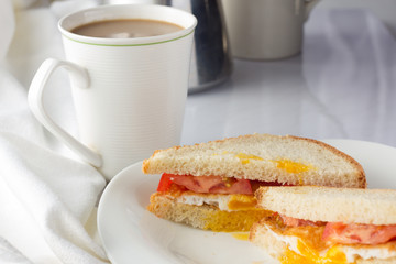 Sandwich with fried egg and tomatoes and cup of coffee