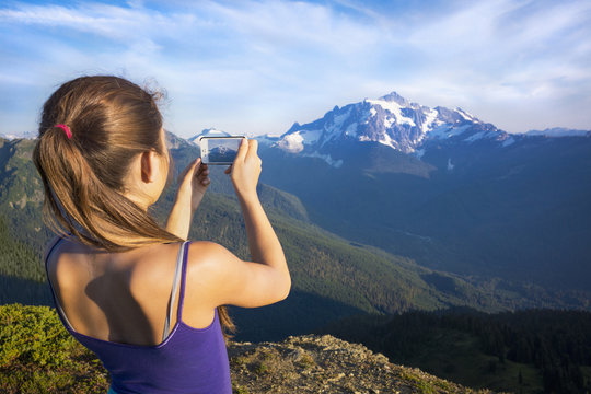 Mixed race girl photographing mountains, North Cascade Mountains, Washington, United States