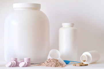 Fototapeta na wymiar Big jar of protein powder, bottle, pills and tablets