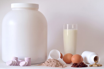 Big jar of protein powder, shaker, milk, pills and tablets