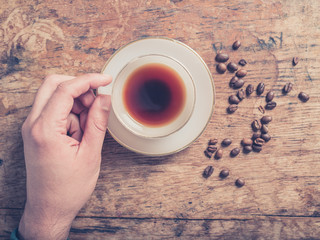 Male hand and coffee with beans on wooden table