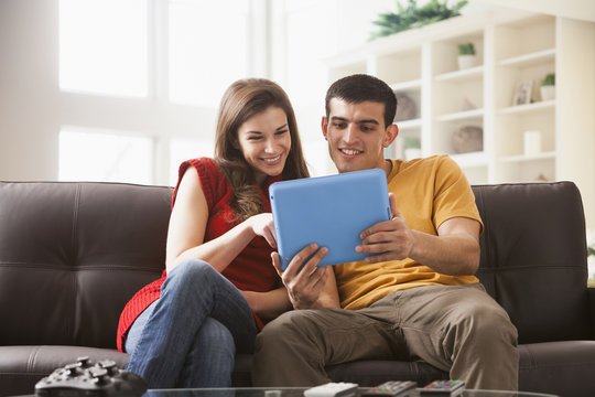 Couple using digital tablet on sofa