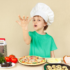 Little funny chef expressive enjoys a cooked pizza