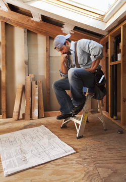 Hispanic construction worker looking at blueprints