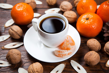 Cup of coffee with tangerines and walnut