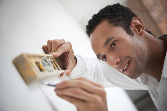 Hispanic carpenter using level on wall