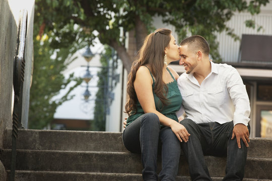 Hispanic woman kissing husband on forehead