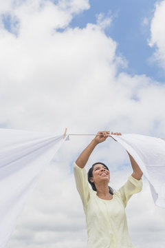 Black woman hanging sheets from clothesline