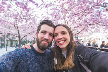 Hipster couple taking a selfie in Stockholm with cherry blossoms