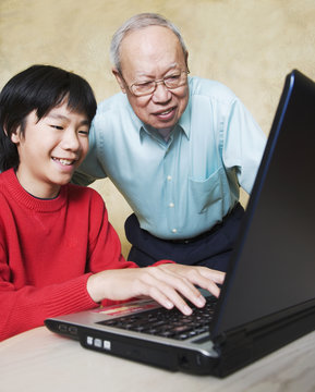 Asian grandfather and grandson looking at laptop