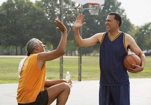 Basketball players high-fiving on basketball court