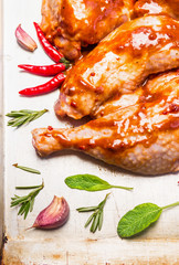 raw chicken legs with red spicy sauce with garlic and sage