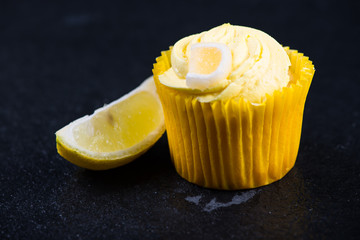 Lemon cupcake decorated with icing on dark background
