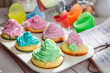 Decorating delicious muffins with cream and decoration