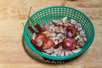 Shallot,garlic and dry chili in basket in wooden chopping block