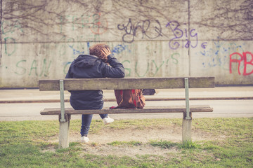 Young girl sitting alone on a bench at park