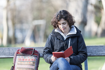 young girl sitting on a bench at park and reading