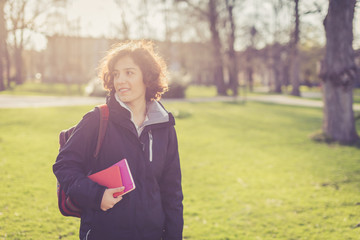 Young student holding books and walking around campus