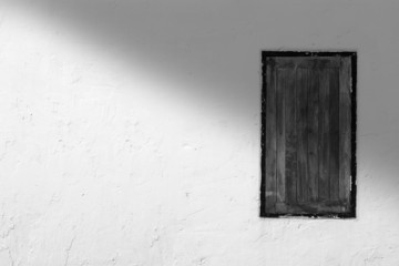 White wall and wood window with shadow from top right