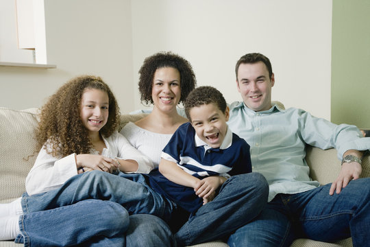 Mixed race family sitting on sofa and smiling