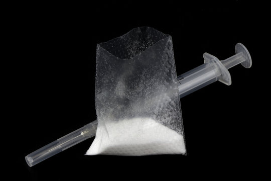 Powder drug and syringe isolated on black