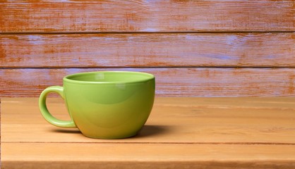 Wooden. Green mug on wooden table over floral wallpaper