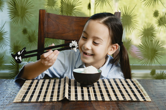 Asian girl eating bowl of rice