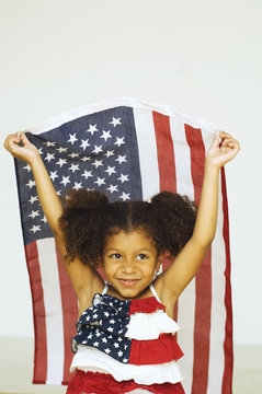 Mixed race girl holding American flag in an American flag dress