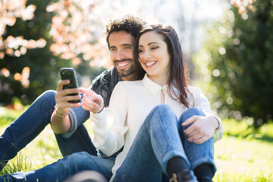Couple looking to a smartphone in a park