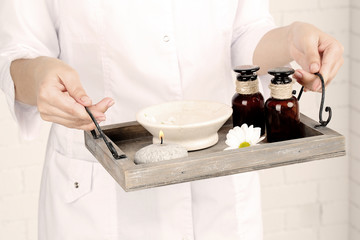 Beauty therapist holding tray of spa treatments, close-up