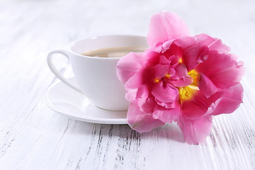 Pink tulip with cup of coffee on wooden background
