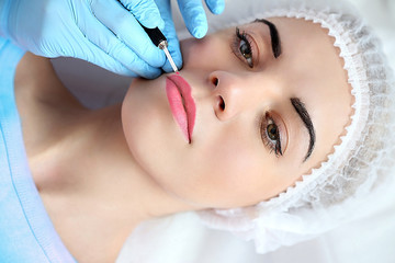 Cosmetologist applying permanent make up on lips - obrazy, fototapety, plakaty