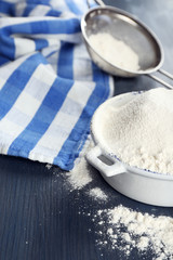 Sifting flour through sieve on wooden table, closeup