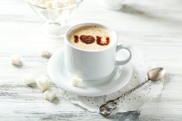 Cup of latte coffee art on wooden table, on light background