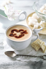 Cup of latte coffee art on wooden table, on light background